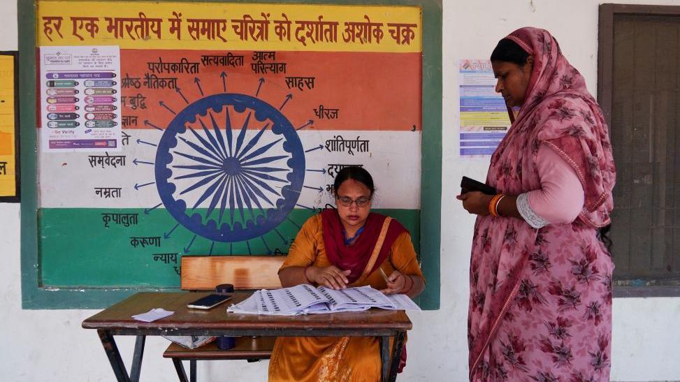 A booth-level officer helps a woman verify her name in the voting list outside a polling station during the state assembly elections, in Karnal, in the northern state of Haryana, India, on October 5, 2024