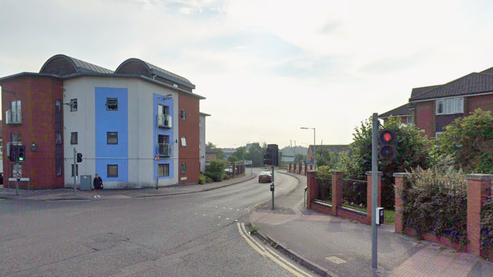 A Google Street View image of a block of flats, a road, and another residential building. Traffic lights are also in the shot.