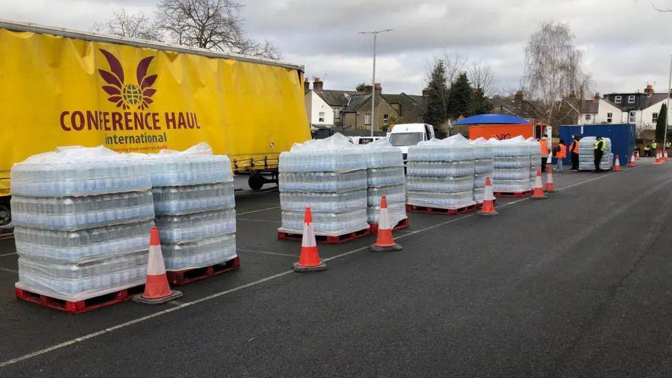 Crates of bottled water lined up in a car park.