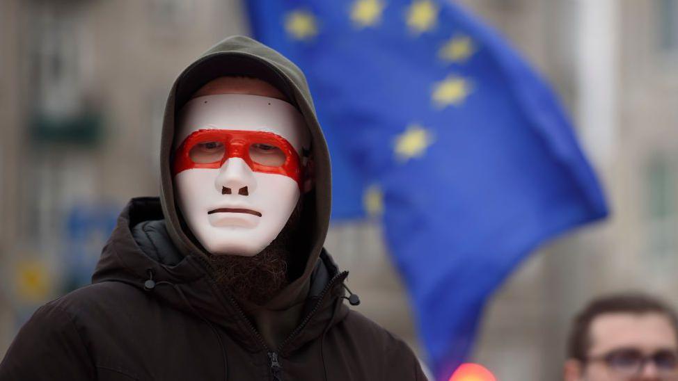 A man wears a mask bearing the colours of the historical flag of Belarus as he takes part in the March of Belarusians in Warsaw, Poland on January 26, 2025.