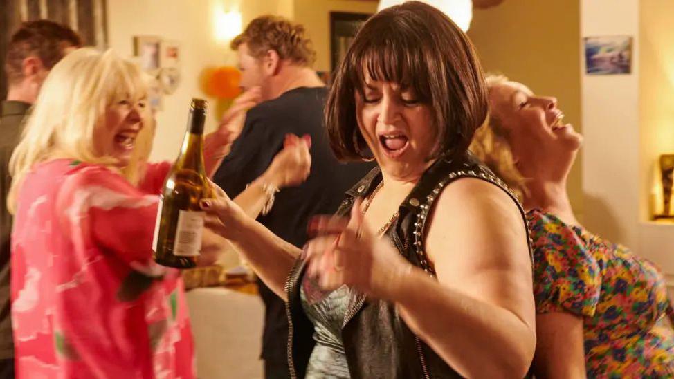 Ruth Jones as Nessa holding a botttle and dancing in Gavin and Stacey Christmas Special 2024
