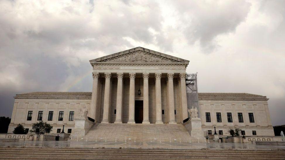 The front of US Supreme Court building with grey clouds above it.