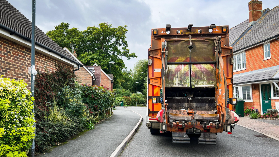 The back of an orange bin lorry in a street.