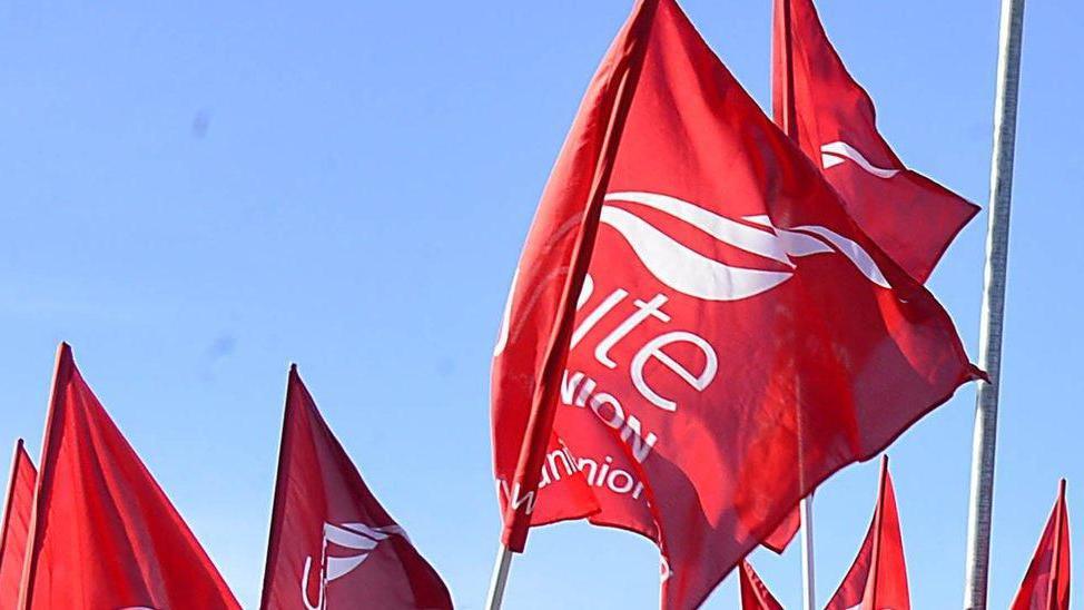 Red large flags flying in the air with the words UNITE UNION in white printed on them