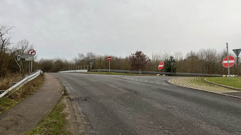 A picture of a bridge over the A5, showing a slip road on the right hand side of the picture. At the entrance to the slip road there are two "no entry" signs, to try to stop drivers going down it the wrong way.