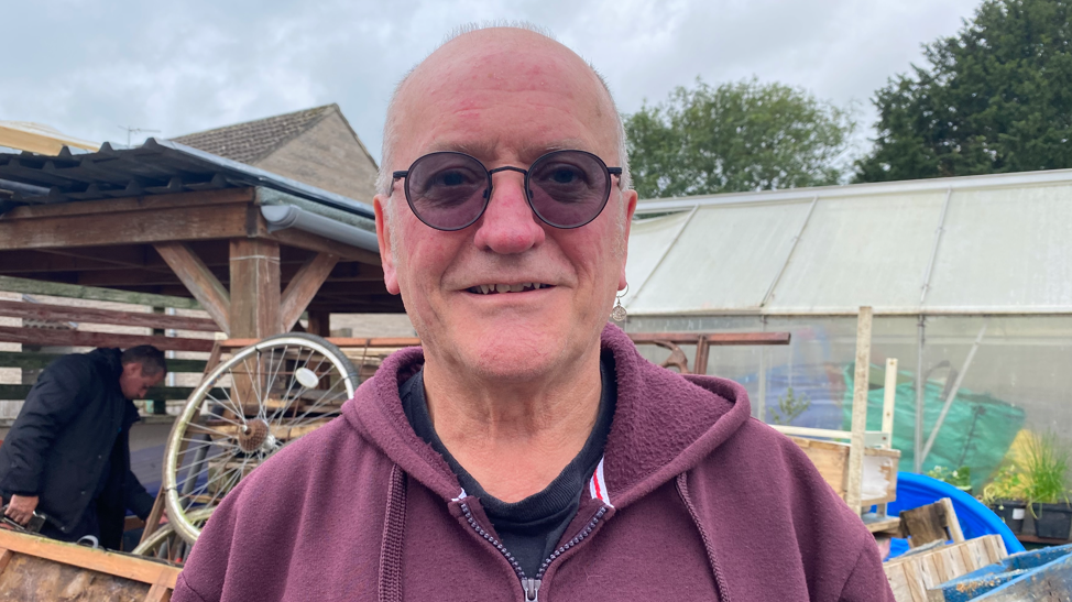 Pete Munday standing in the new space outside the United Reformed Church in Glastonbury.  He is wearing sunglasses and a purple hoodie.