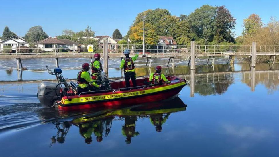 Fire and rescue officers on a boat on Thames at Sunbury as part of rescue operation 