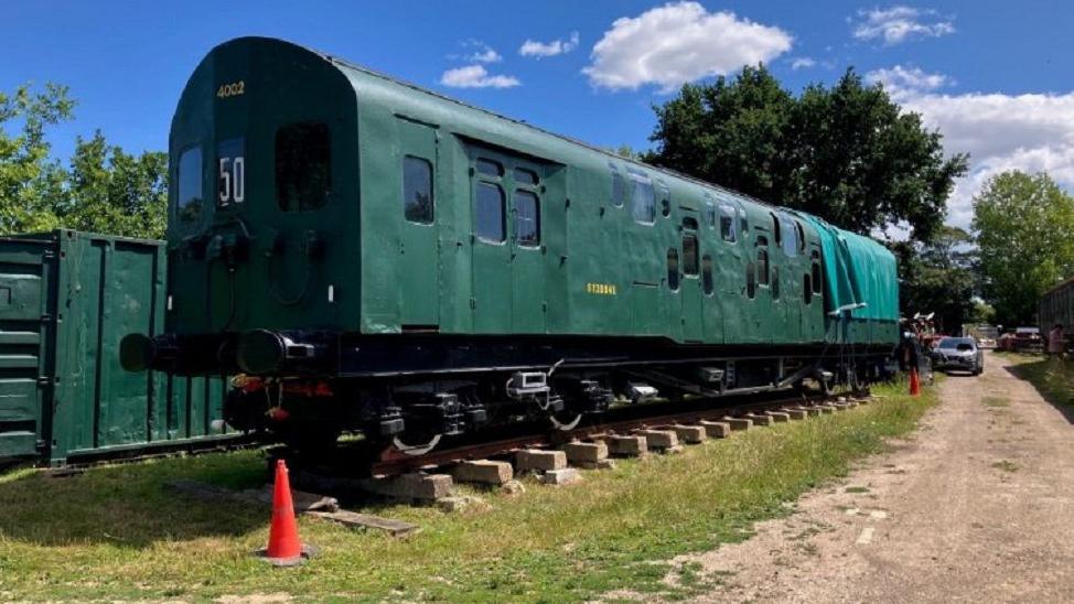 Britain's only double decker train was Bulleid's 4DD, which is being restored and is pictured. It is a dark green colour and is pictured on a track with cones around it. 