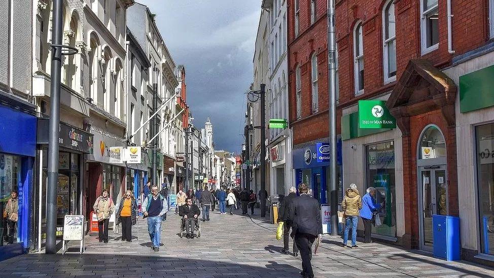 Businesses along strand street and people walking along the street