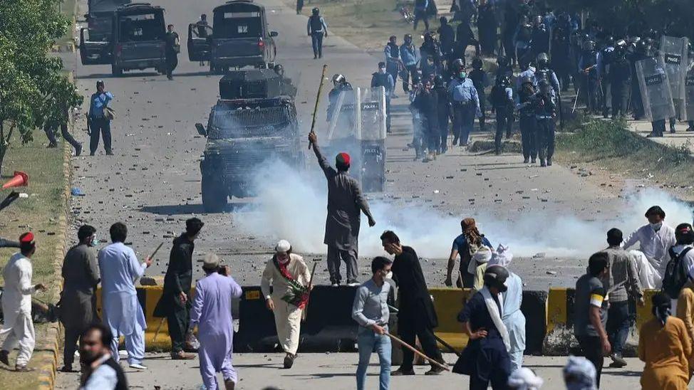 Image shows supporters of jailed former Pakistan prime minister Imran Khan being pushed back by security forces during violent protests in May 2023