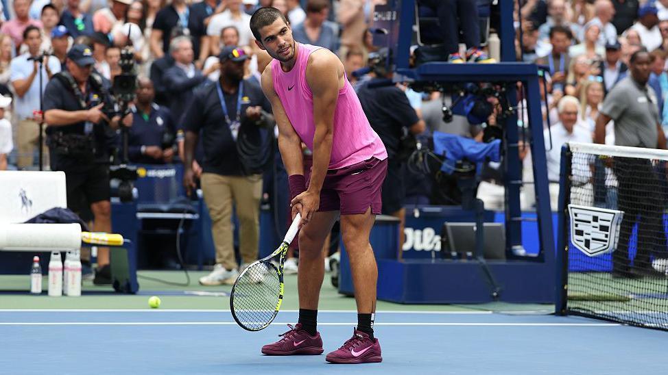 Carlos Alcaraz mimics a golf swing with a tennis racquet at the US Open