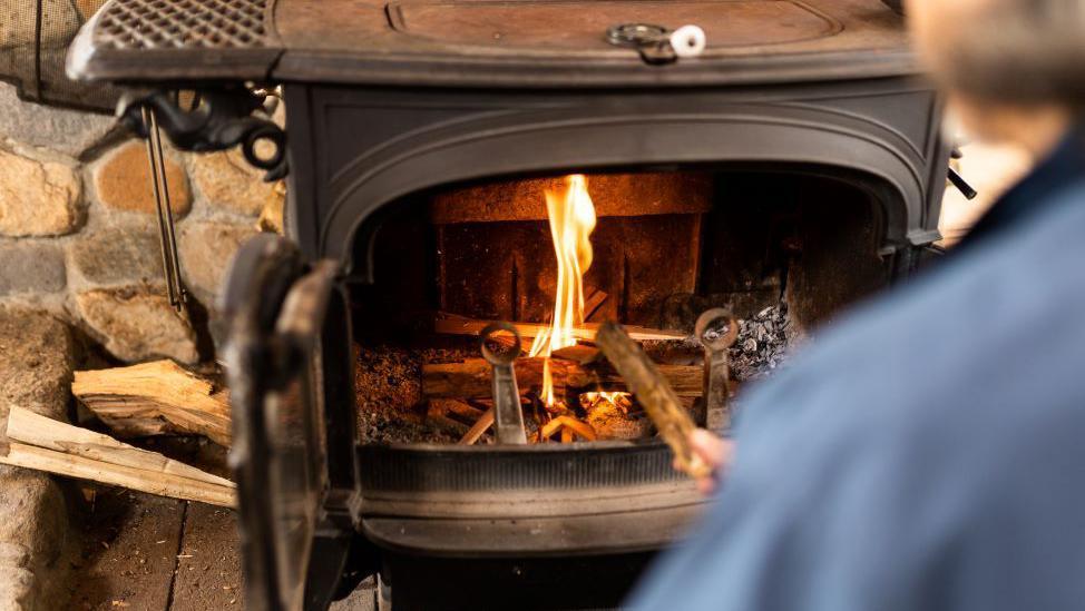 A person pokes the fire in a log burner 