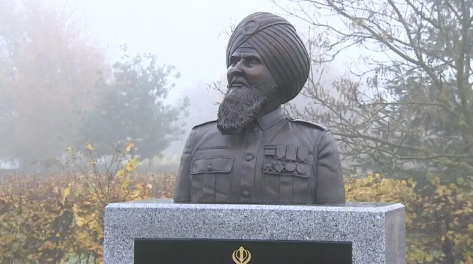 A head and shoulders statue of a Sikh man with a turban sits atop a stone memorial and plaque at the arboretum.