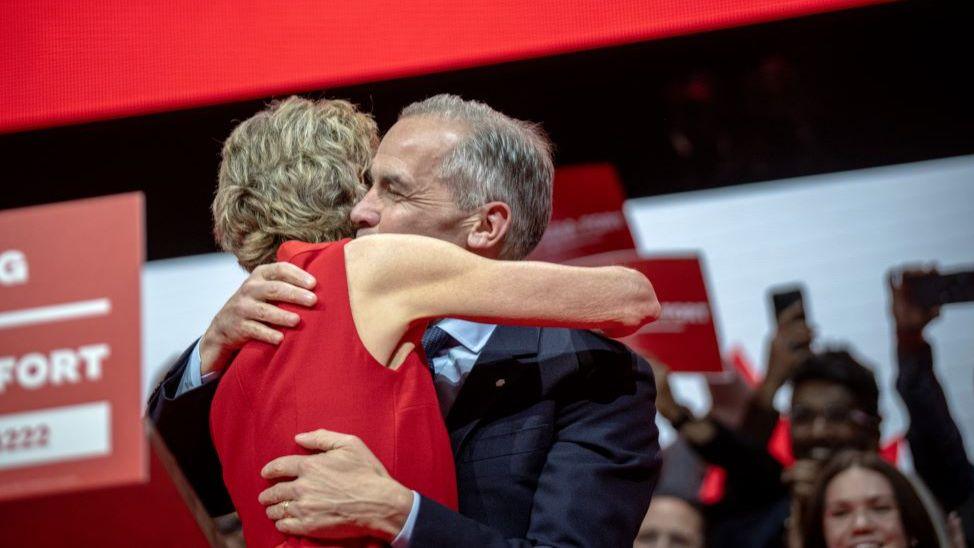 Mark Carney receives an embrace in front of cheering supporters after victory