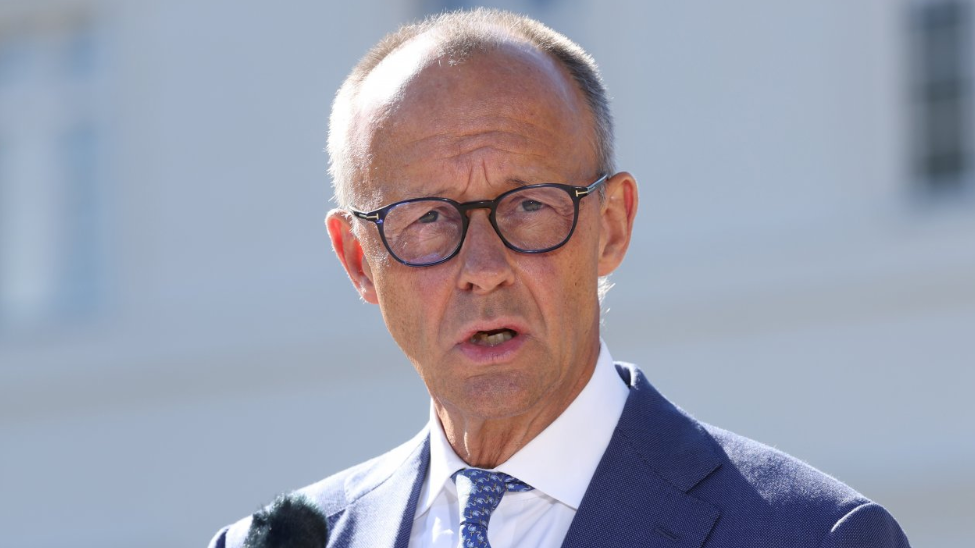 Friedrich Merz speaks wearing a blue suit to journalists on 25 August 2026