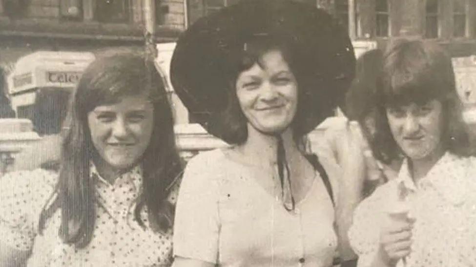 A black-and-white image of two young girls, Jane Tallon and Jackie Hallam,  standing either side of Lorna Bryson Norton. They all have long dark hair and are wearing light coloured blouses. Lorna is wearing a large rimmed dark coloured hat and Jackie is holding an ice-cream cone.