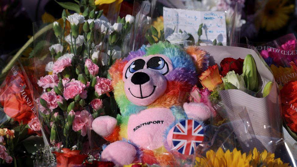 A colourful teddy which has 'Southport' on its belly nestled in flowers 