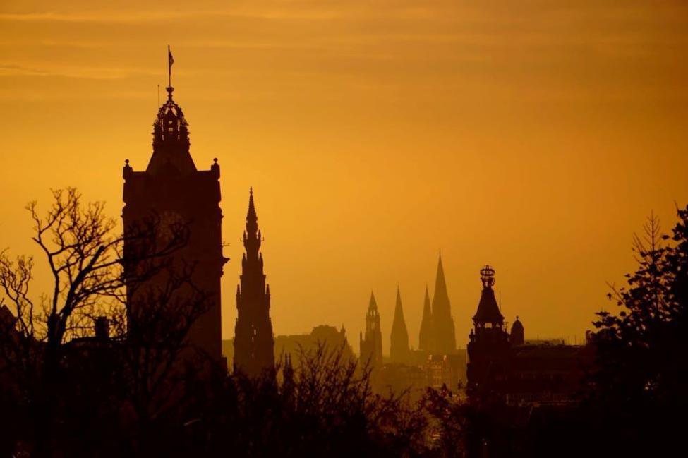 Church spires and roof tops set against a warm orange sky.