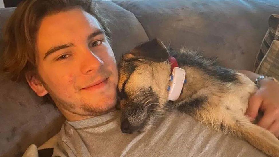 A closeup of a young man cuddling a dog