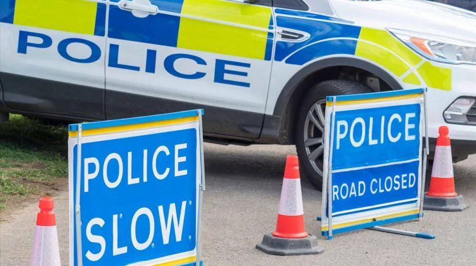 A police car next to two road closures sign