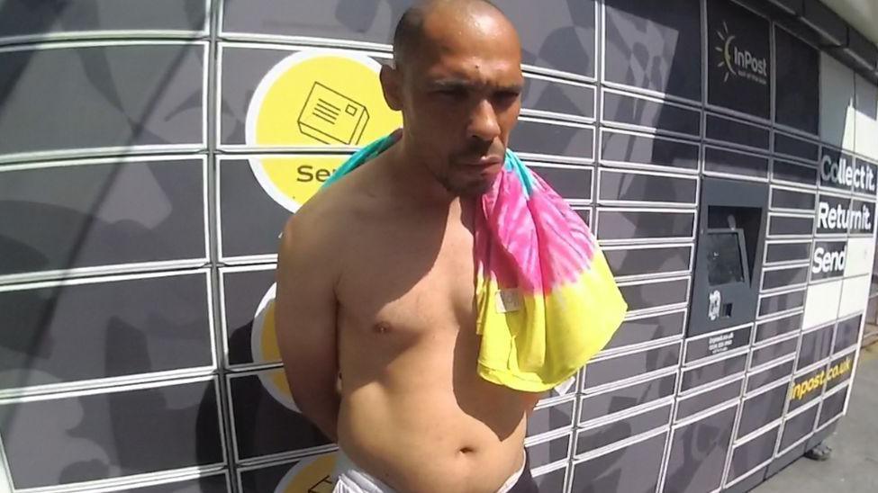 A topless man with his hands behind his back