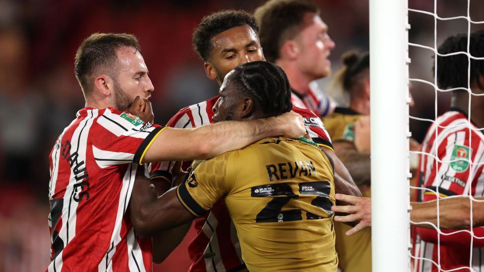 Sebastian Revan of Wrexham clashes with Rhys Norrington-Davies of Sheffield United