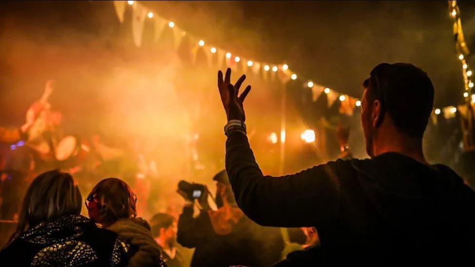 A crowd of people dancing at a festival at night