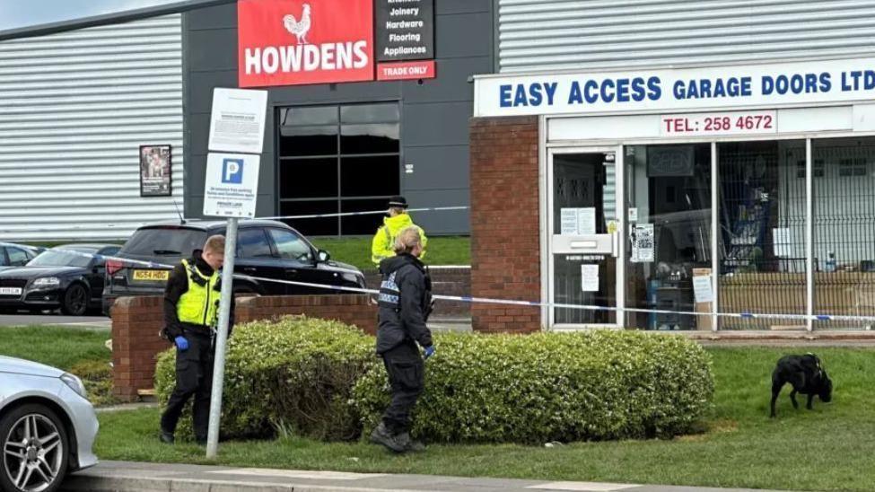 Police officers at the scene of Mr Darn's death on the Tyne Tunnel Trading Estate. There is a police cordon in place around the reception of a garage and there are three officers and a dog outside.