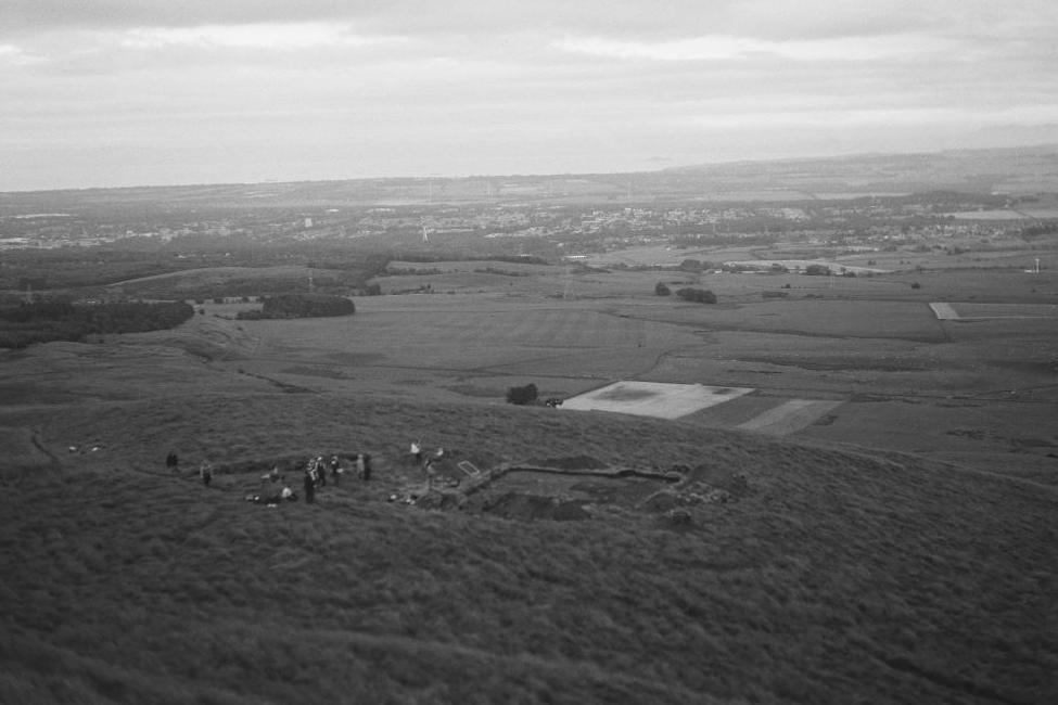 Archaeologists on the hilltop dig site with the Fife landscape behind it