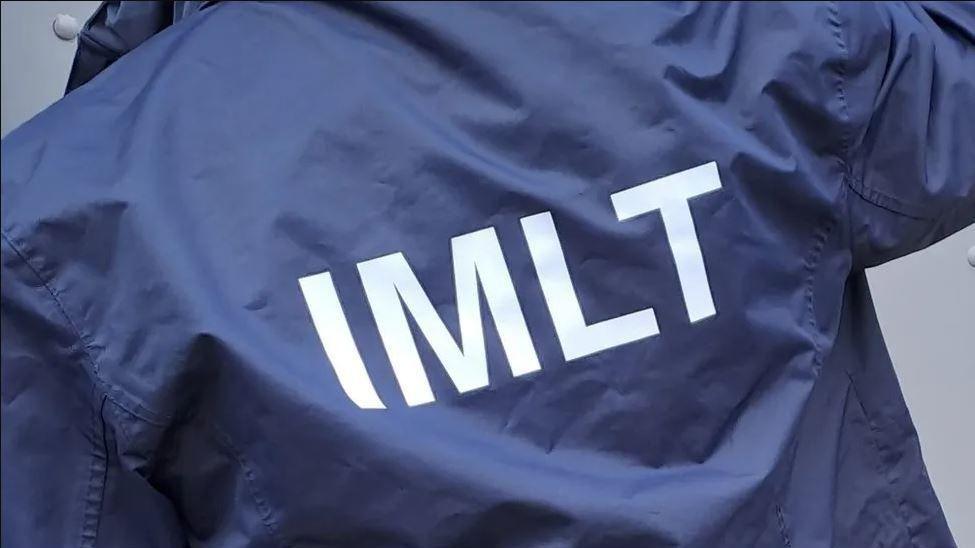 A blue jacket with IMLT emblazoned in white lettering across it.