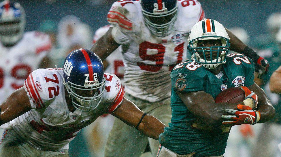 Travis Daniels of the Miami Dolphins runs with the ball while being pursued by Osi Umenyiora of the New York Giants at Wembley in 2007