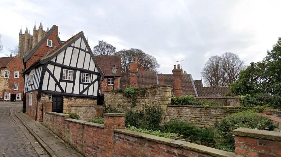 The Tudor-style building, known as the Wonky House, leaning to the right. Lincoln Cathedral can be seen in the background.