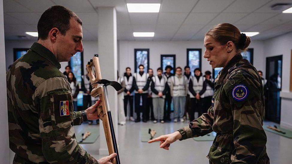Military instructors provide guidance to participants during a laser shooting training session in France