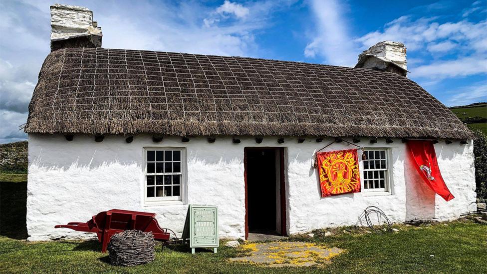 A traditional white cottage with thatched roof.