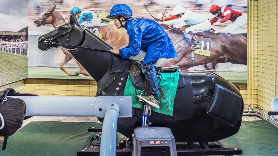 A young visitor dressed as a jockey rides an animatronic racehorse at the Palace House.