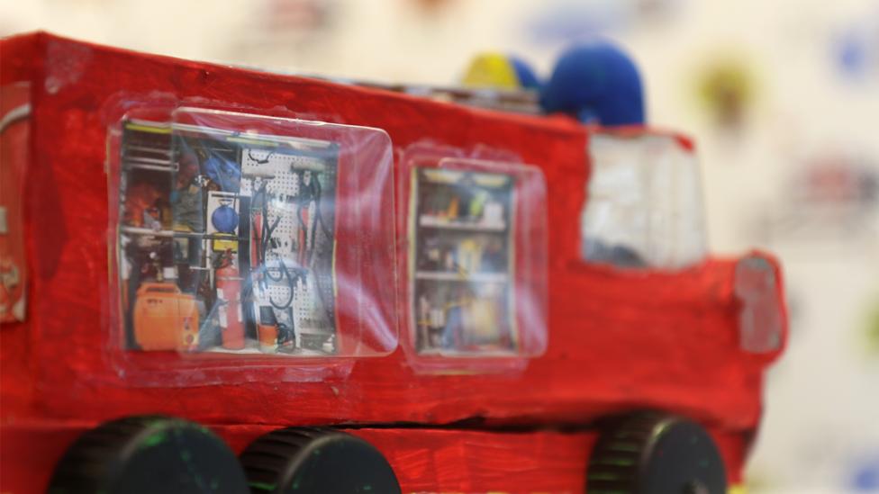 The side of the fire engine, showing the images of equipment stuck to the side.
