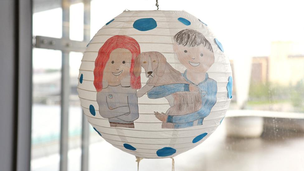 A close-up of the cartoon drawing of Lindsey, Richie and Henry on the side of the lantern.