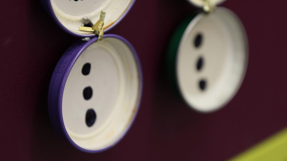 The edges of two of the lids, showing colourful purple paint.