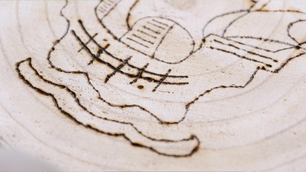 A close-up of the detailed Blue Peter ship, carved into the log slice. Made by Macey from Bridgend, Wales.