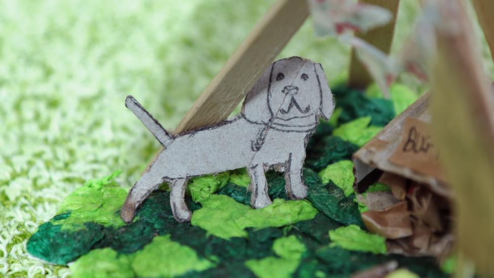 A close-up of the cardboard mini Henry dog, stood in the garden.