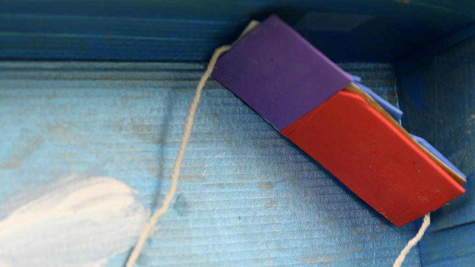 A close-up of the purple, red and blue kite, with two strings attached to it.