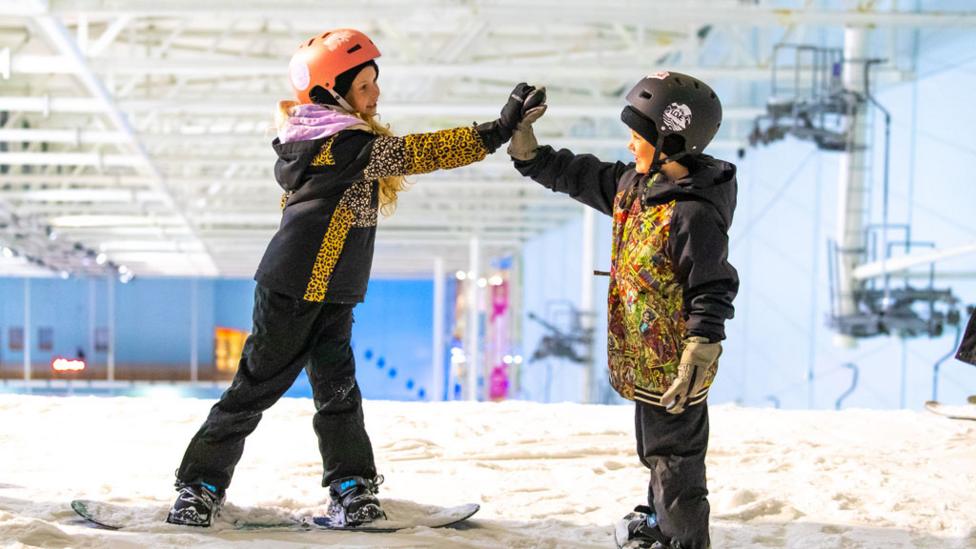 two_young_snowboarders_high_fiving.
