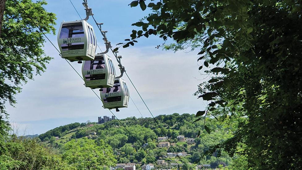 three-cable-cars-surrounded-by-blue-sky-and-greenery.