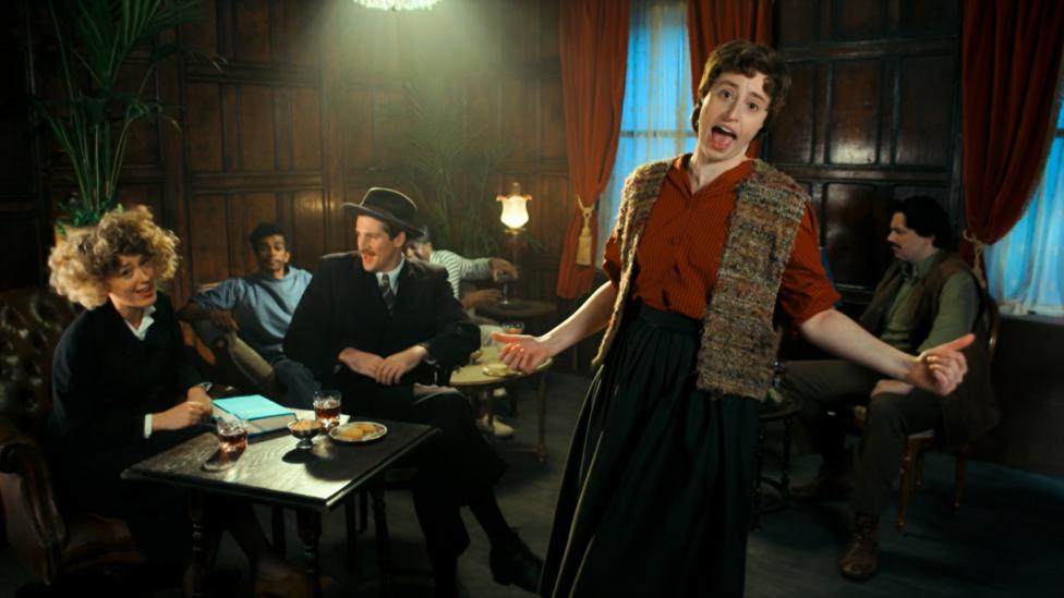 Image of Horrible Histories characters in a dimly lit room in 1920s dress