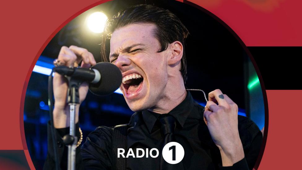 Yungblud, a young man dressed in black with slicked black hair.