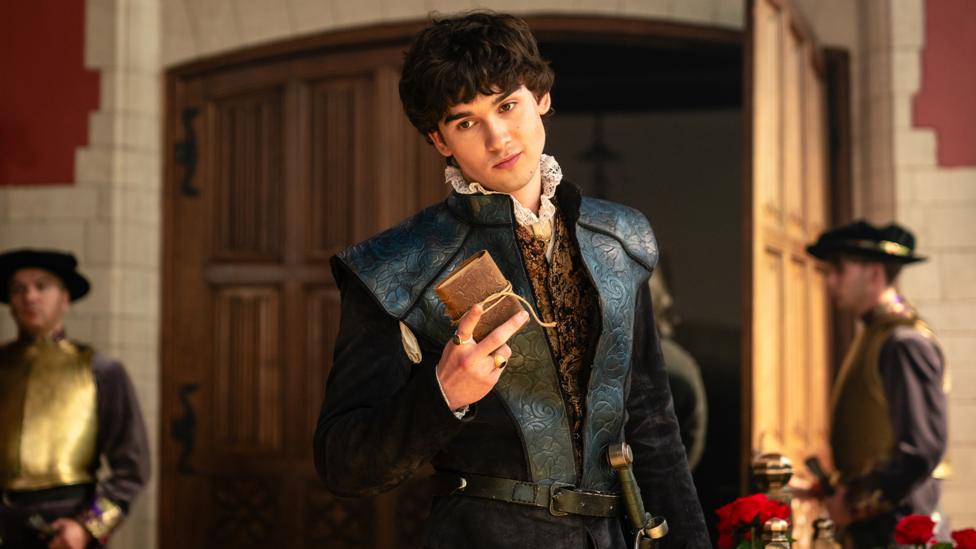 Image of a man dressed in a black Tudor outfit holding a package wrapped in a string.