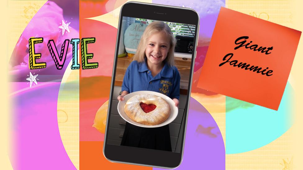 A little girl called Evie smiles as she holds up a plate filled with a giant Jammie biscuit.