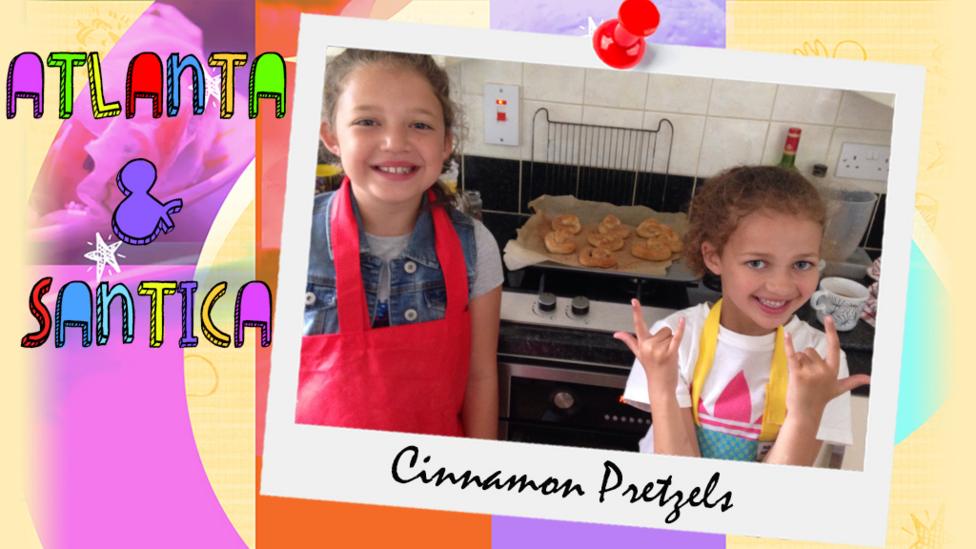 Two girls (Atlanta and Santica) stand in front of a tray full of cinnamon pretzels.