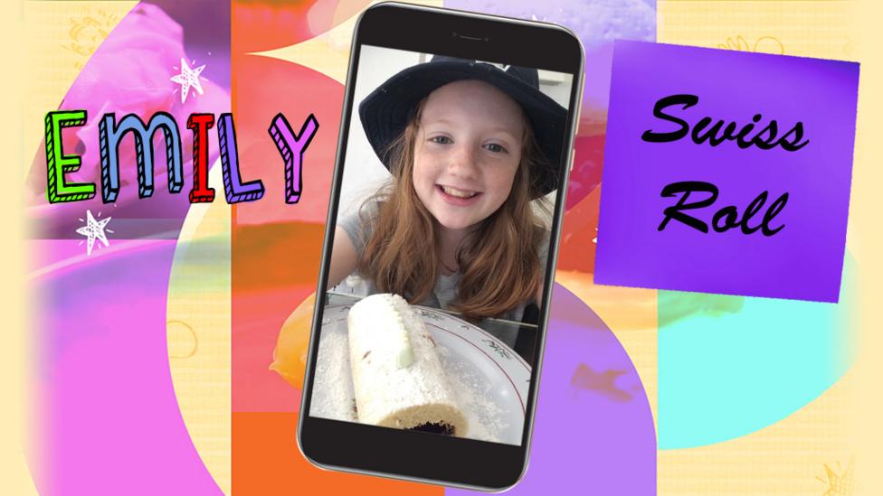 A little girl (Emily) smiling and holding up a plate containing a swiss roll.