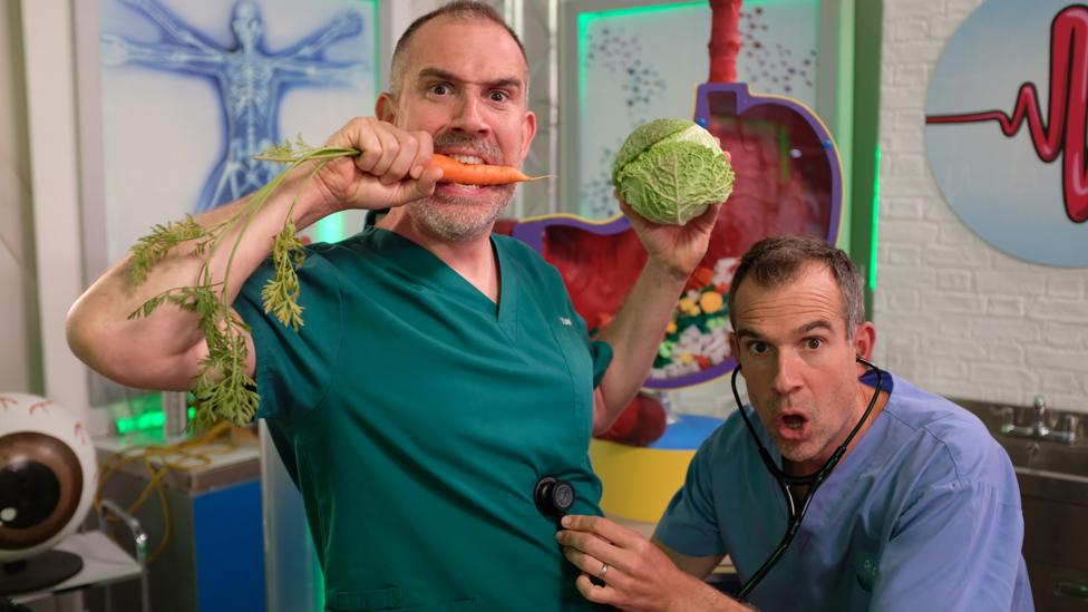 Dr Chris and Dr Xand hold vegetables in the lab.